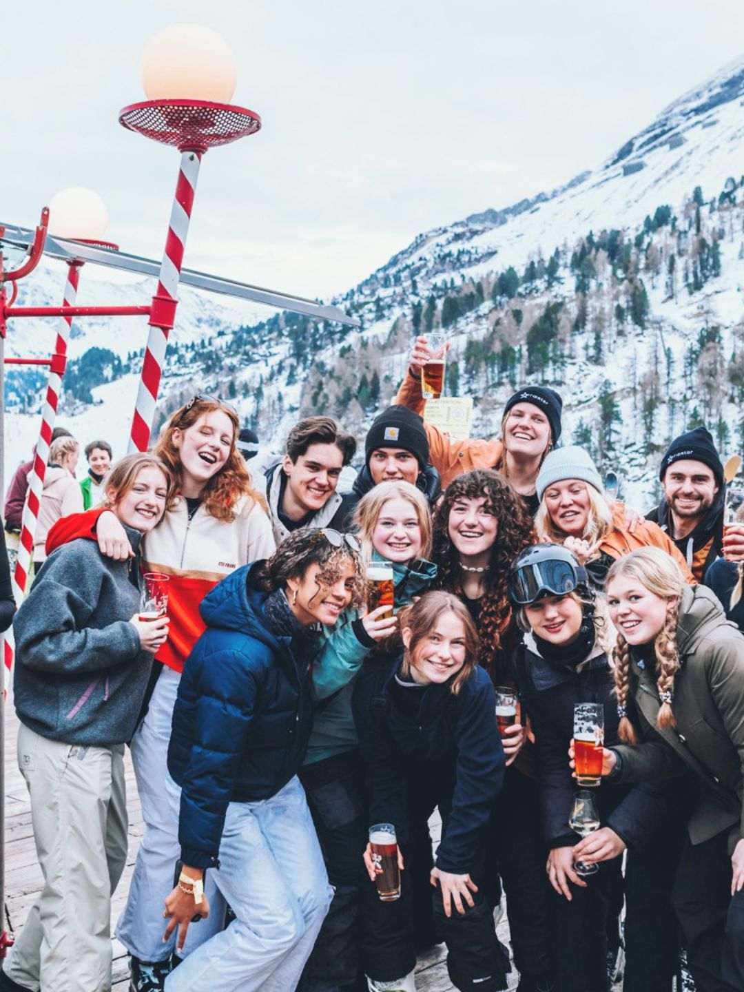 Groep jonge mensen met een drankje op een zonnig terras in de sneeuw